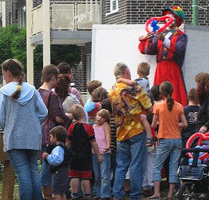 Ballonkünstler als Clown auf Stelzen modelliert Luftballons am Stadtfest